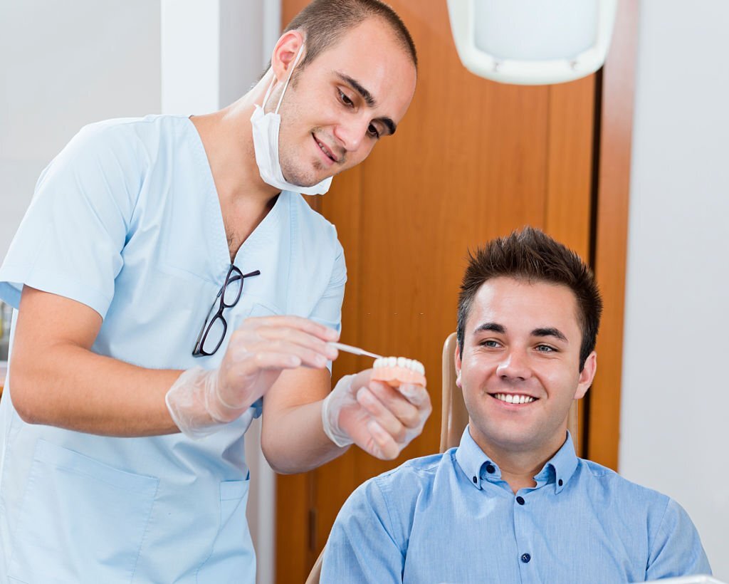 Dentist assisting a male patient