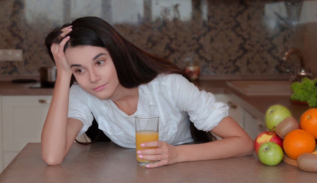 girl in the morning in the kitchen drinks delicious sveha drunk orange juice