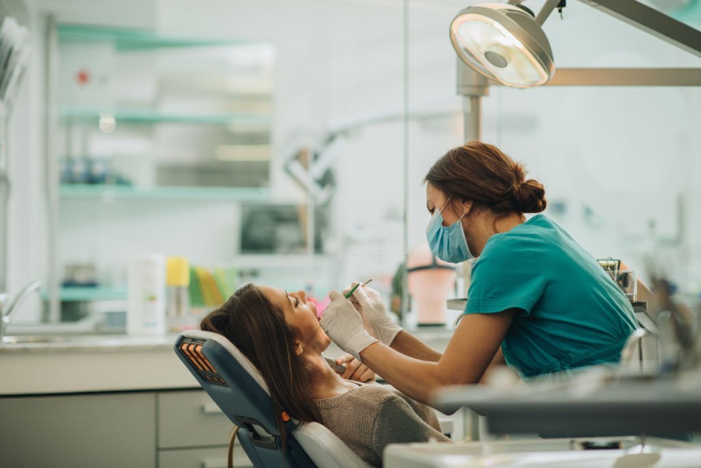 Female dentist examining young woman's teeth.